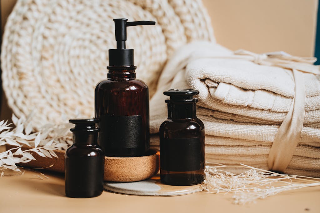 Brown Bottles and Dried White Flowers Near Folded Towels