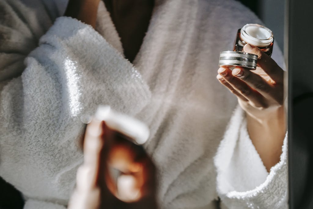 Crop ethnic woman with jar of cream against mirror checking whether it is organic vs natural skincare