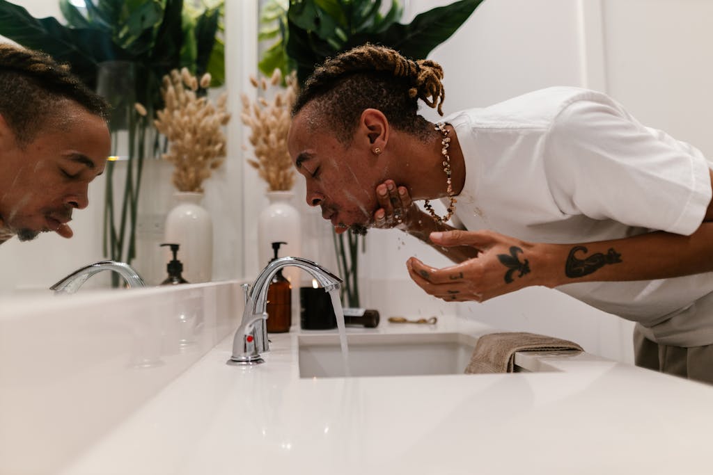 Man Washing Face with the oil cleansing method at Bathroom Sink