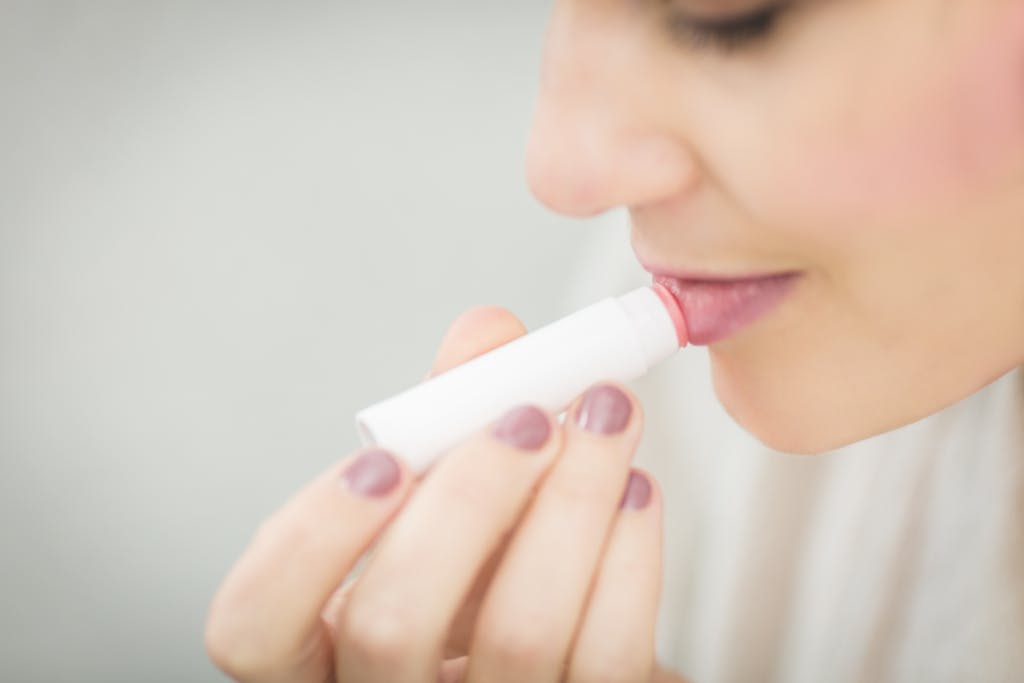 Woman Putting on rose-tinted lip balm