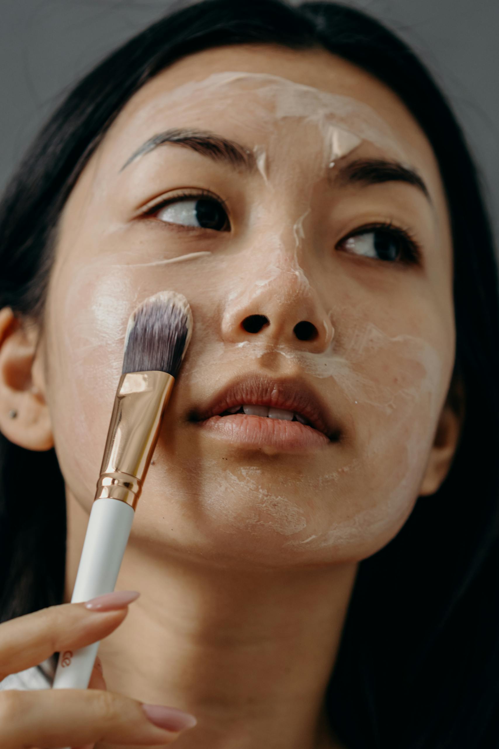 A Close-up Shot of a Woman Applying a Cream on Her Face