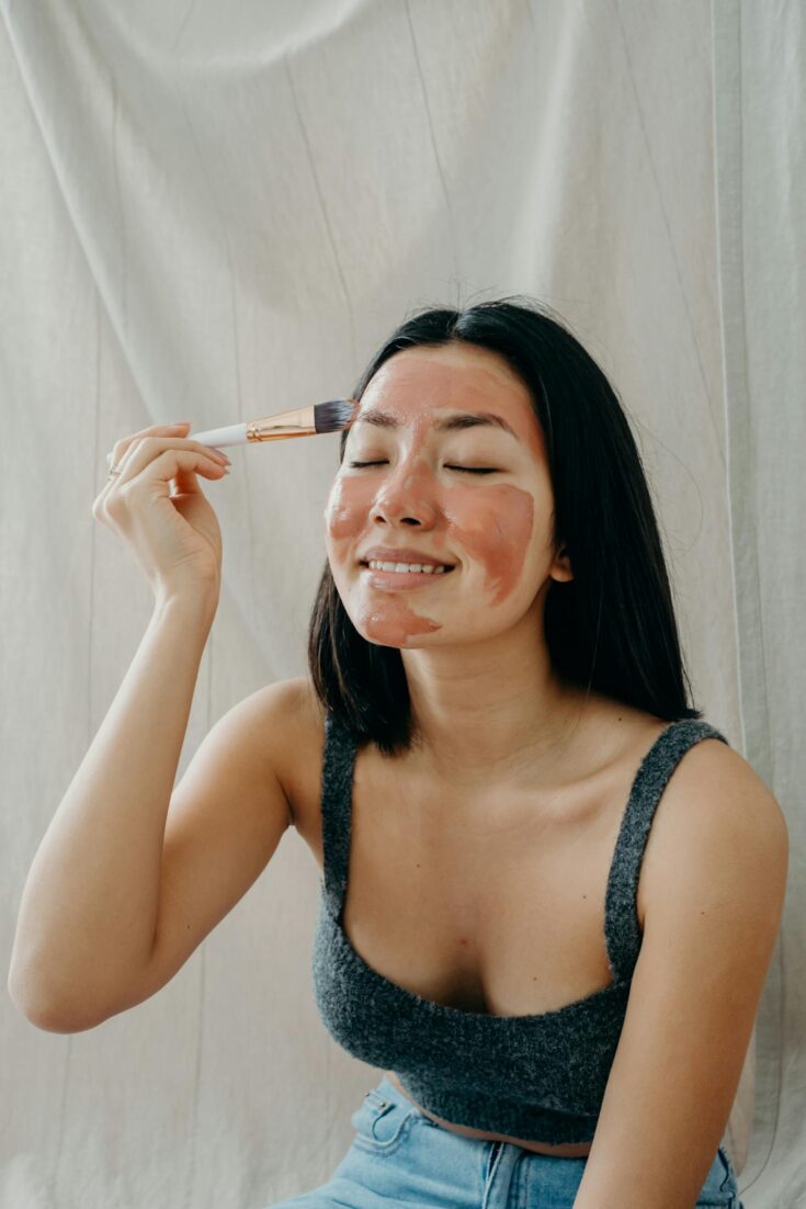 A Woman in Gray Tank Top Doing Her Skin Care with Her Eyes Closed